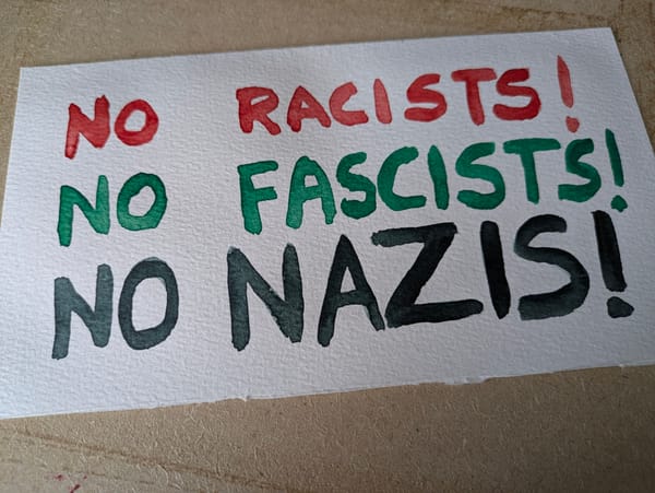Banner with text: "No Racists! No Fascists! No Nazis!" in Red, Green, and Black respectively. 